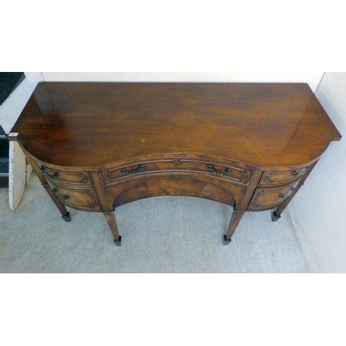 177 - A mid 20thC mahogany finished serpentine front sideboard, comprising an arrangement of drawers and c... 
