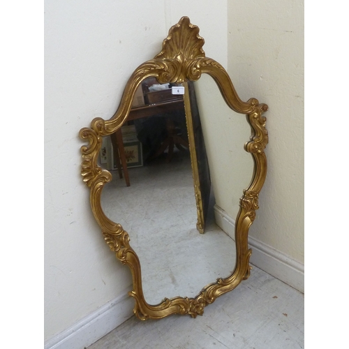 6 - A modern Continental inspired mirror, the shaped plate in a shell and C-scroll moulded gilt frame  3... 
