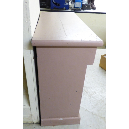 24 - An early 20thC pink painted pine chiffonier with a frieze drawer, over a pair of floral carved panel... 