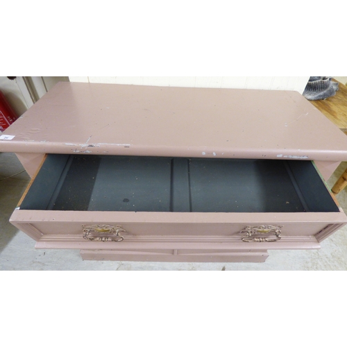 24 - An early 20thC pink painted pine chiffonier with a frieze drawer, over a pair of floral carved panel... 