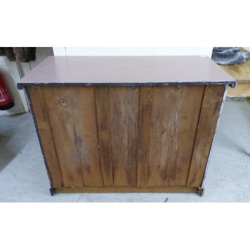 24 - An early 20thC pink painted pine chiffonier with a frieze drawer, over a pair of floral carved panel... 