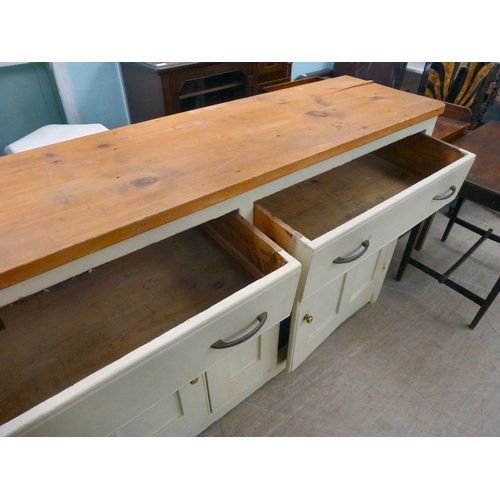 20 - A late 19thC and later cream painted wooden sideboard, the showwood pine surface over two drawers/tw... 