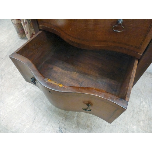 22 - An early 20thC string inlaid mahogany serpentine front chest of drawers, raised on tapered legs and ... 