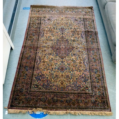 58 - A Persian part-silk rug, decorated with dense flora, on a maroon ground  80