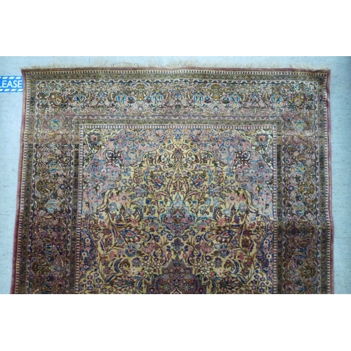58 - A Persian part-silk rug, decorated with dense flora, on a maroon ground  80