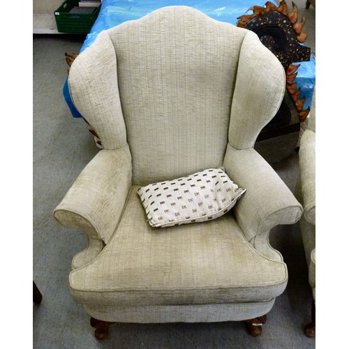 60 - Two similar modern wingback arm chairs, upholstered in beige fabric, raised on cabriole legs
