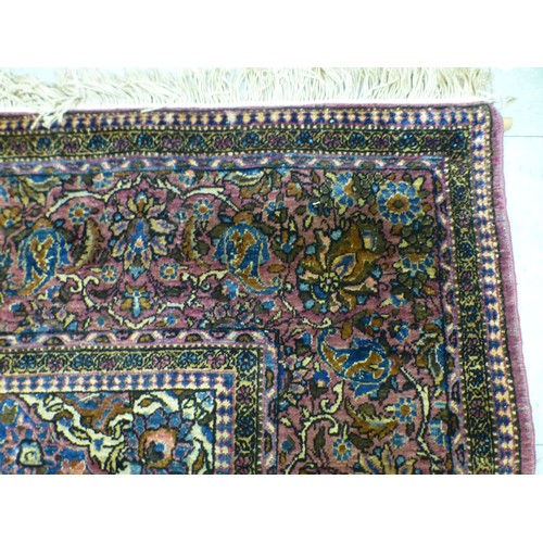 58 - A Persian part-silk rug, decorated with dense flora, on a maroon ground  80