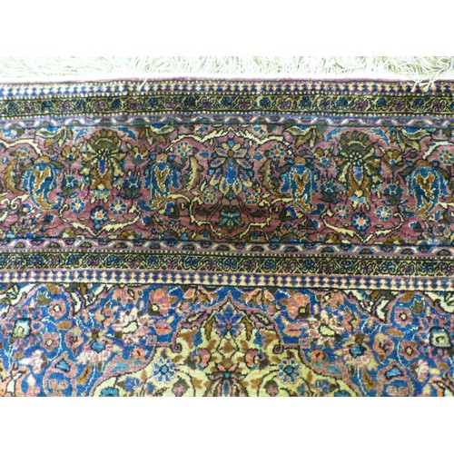 58 - A Persian part-silk rug, decorated with dense flora, on a maroon ground  80