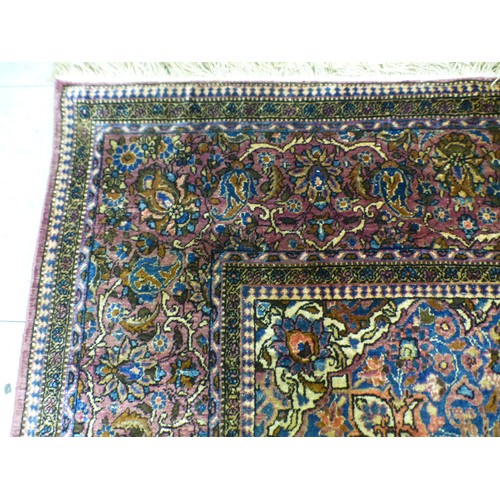 58 - A Persian part-silk rug, decorated with dense flora, on a maroon ground  80
