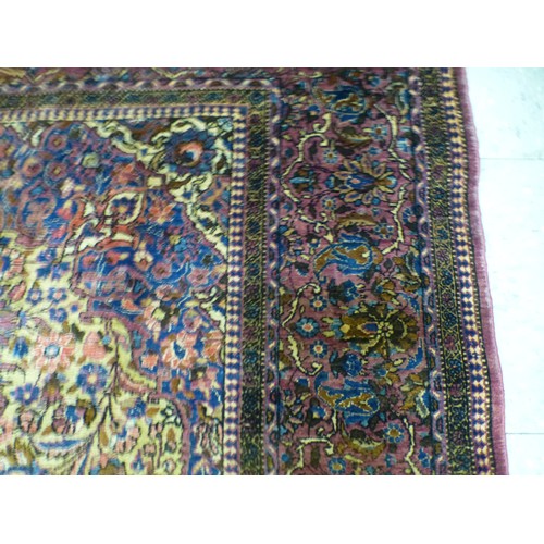 58 - A Persian part-silk rug, decorated with dense flora, on a maroon ground  80