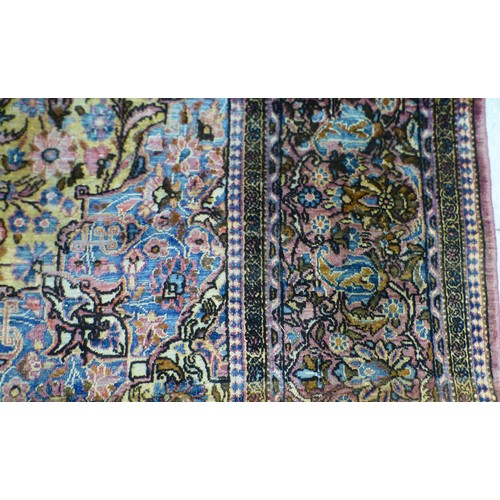 58 - A Persian part-silk rug, decorated with dense flora, on a maroon ground  80