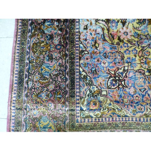 58 - A Persian part-silk rug, decorated with dense flora, on a maroon ground  80