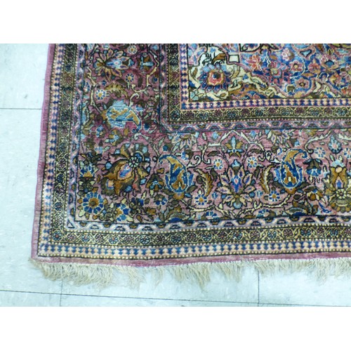 58 - A Persian part-silk rug, decorated with dense flora, on a maroon ground  80