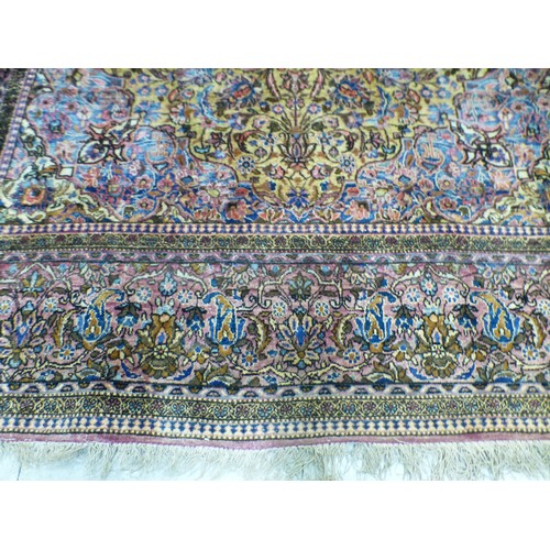 58 - A Persian part-silk rug, decorated with dense flora, on a maroon ground  80