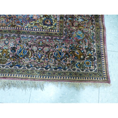 58 - A Persian part-silk rug, decorated with dense flora, on a maroon ground  80