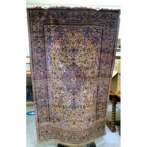 58 - A Persian part-silk rug, decorated with dense flora, on a maroon ground  80