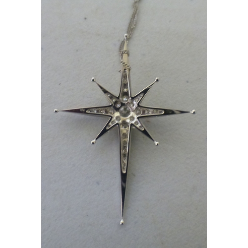 A white metal star design, diamond set pendant stamped 18k, on a white ...