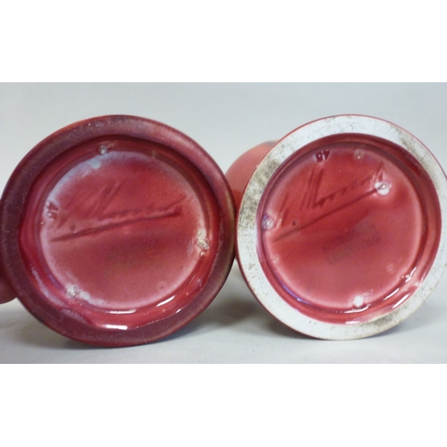 39 - A pair of Moorcroft pottery Liberty vases, each decorated with Art Nouveau floral motifs, on a red g... 