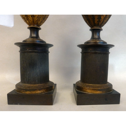 37 - A pair of late 19thC Empire design cast metal, urn design vases/candlesticks, on a plinth  14.5
