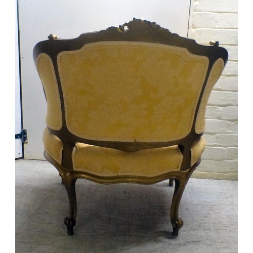 27 - A 20thC reproduction of an 18thC Continental gilt sprayed showwood salon chair, upholstered in flora... 