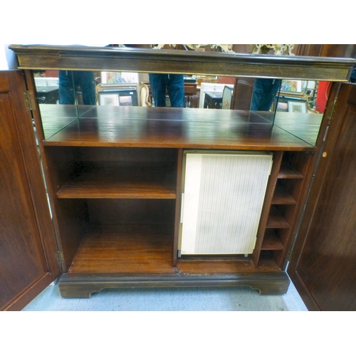 290 - An early/mid mahogany drinks cabinet with a pair of panelled doors, enclosing open shelves and a ref... 