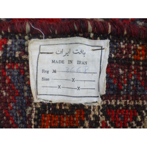 120 - A Persian rug, decorated with three central diamond shaped motifs, bordered by stylised designs, on ... 