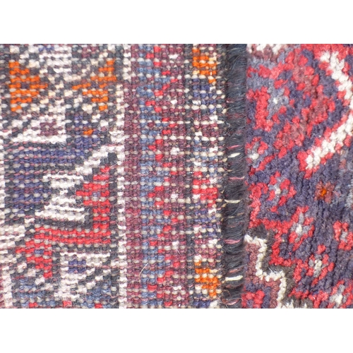 120 - A Persian rug, decorated with three central diamond shaped motifs, bordered by stylised designs, on ... 