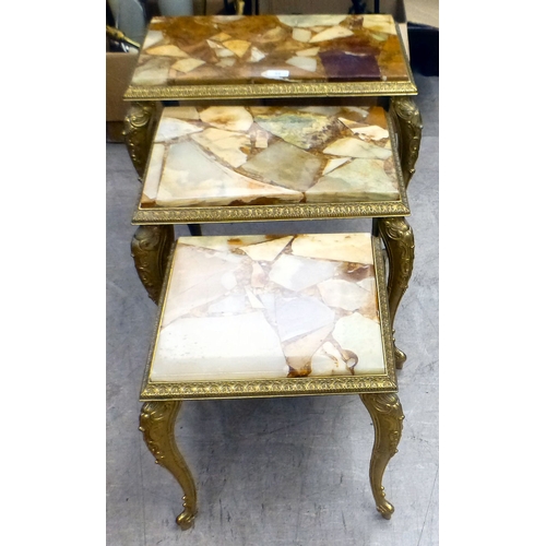 98 - A modern nesting set of three gilt metal framed tables with hardstone and resin surfaces, raised on ... 
