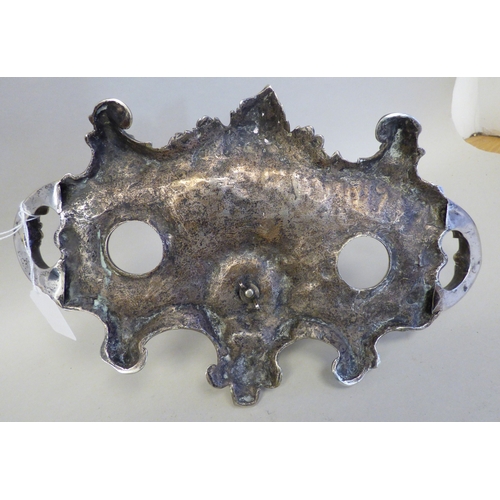 19 - An early 20thC cast white metal inkstand, surmounted by a white metal on copper military figure, kne... 