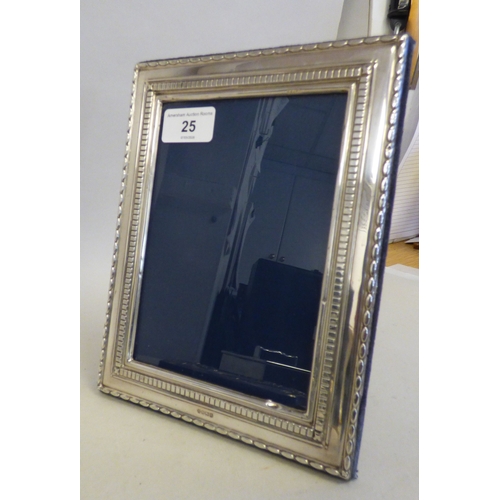 25 - A silver photograph frame with two patterned bordered ornament, on a fabric easel back  4.5