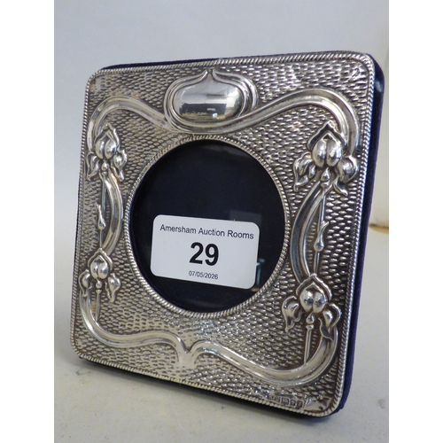 29 - An Art Nouveau silver photograph frame with floral and whiplash ornament  London 1913 the central ca... 