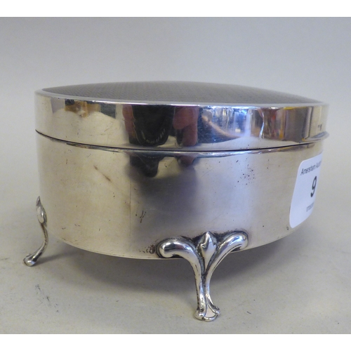 9 - A George V silver oval ring box with engine turned decoration, enclosing a fabric lined fitted inter... 