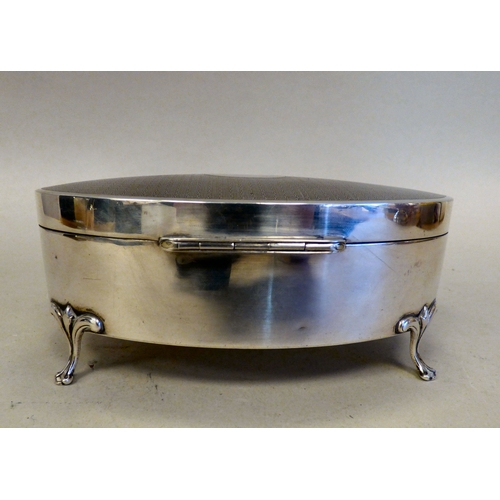 9 - A George V silver oval ring box with engine turned decoration, enclosing a fabric lined fitted inter... 