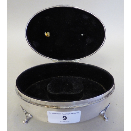 9 - A George V silver oval ring box with engine turned decoration, enclosing a fabric lined fitted inter... 