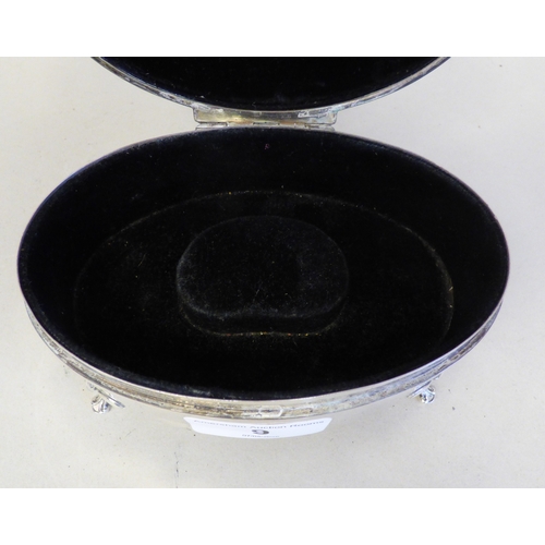 9 - A George V silver oval ring box with engine turned decoration, enclosing a fabric lined fitted inter... 