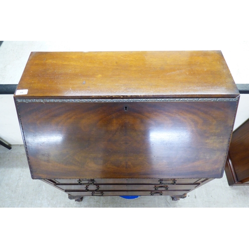 44 - An early 20thC mahogany bureau with a fall flap, over three graduated drawers, raised on carved, stu... 