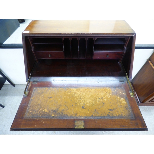 44 - An early 20thC mahogany bureau with a fall flap, over three graduated drawers, raised on carved, stu... 