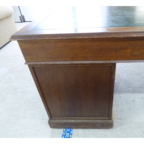 46 - An early 20thC oak nine drawer, twin pedestal desk, on a plinth&nbsp; 30