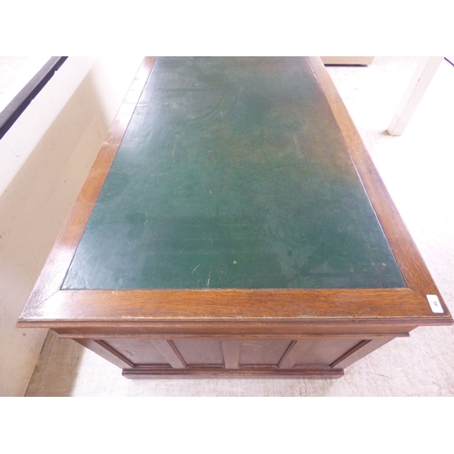 46 - An early 20thC oak nine drawer, twin pedestal desk, on a plinth&nbsp; 30
