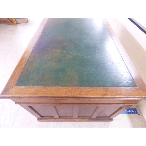 46 - An early 20thC oak nine drawer, twin pedestal desk, on a plinth&nbsp; 30