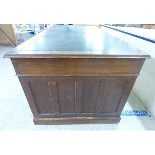 46 - An early 20thC oak nine drawer, twin pedestal desk, on a plinth&nbsp; 30