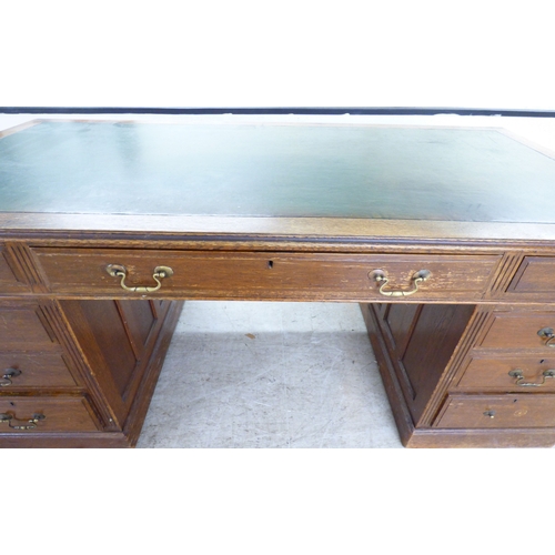 46 - An early 20thC oak nine drawer, twin pedestal desk, on a plinth&nbsp; 30