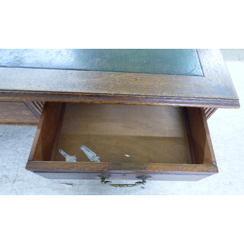 46 - An early 20thC oak nine drawer, twin pedestal desk, on a plinth&nbsp; 30