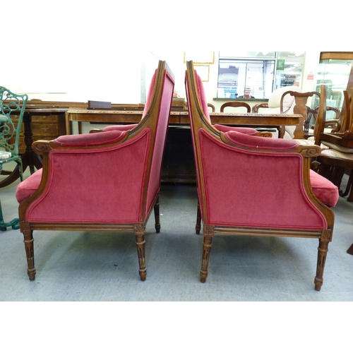 51 - A pair of 20thC antique reproduction, carved beech and mahogany enclosed armchairs, upholstered in p... 