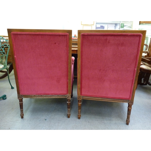 51 - A pair of 20thC antique reproduction, carved beech and mahogany enclosed armchairs, upholstered in p... 