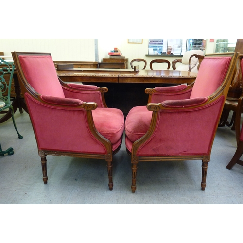 51 - A pair of 20thC antique reproduction, carved beech and mahogany enclosed armchairs, upholstered in p... 