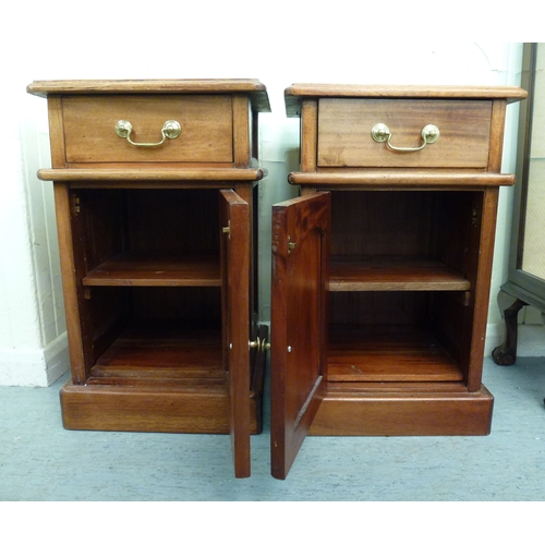 52 - A pair of modern fruitwood bedside chests with a single drawer, over a panelled door, raised on a pl... 