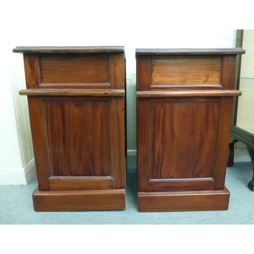 52 - A pair of modern fruitwood bedside chests with a single drawer, over a panelled door, raised on a pl... 