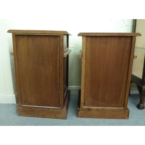 52 - A pair of modern fruitwood bedside chests with a single drawer, over a panelled door, raised on a pl... 