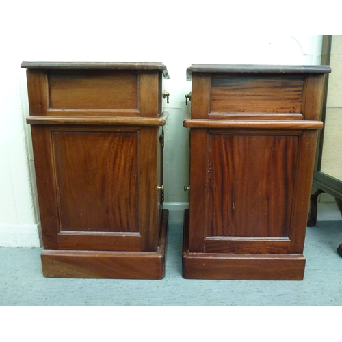 52 - A pair of modern fruitwood bedside chests with a single drawer, over a panelled door, raised on a pl... 